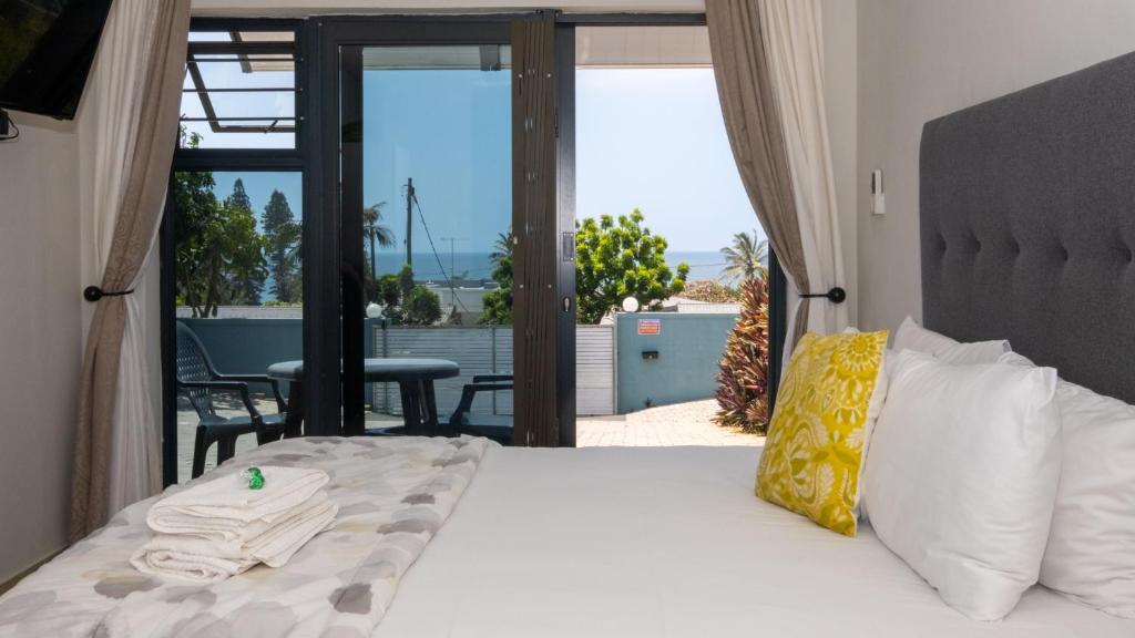 Double bed with white linen and doors opening towards a sea-view patio