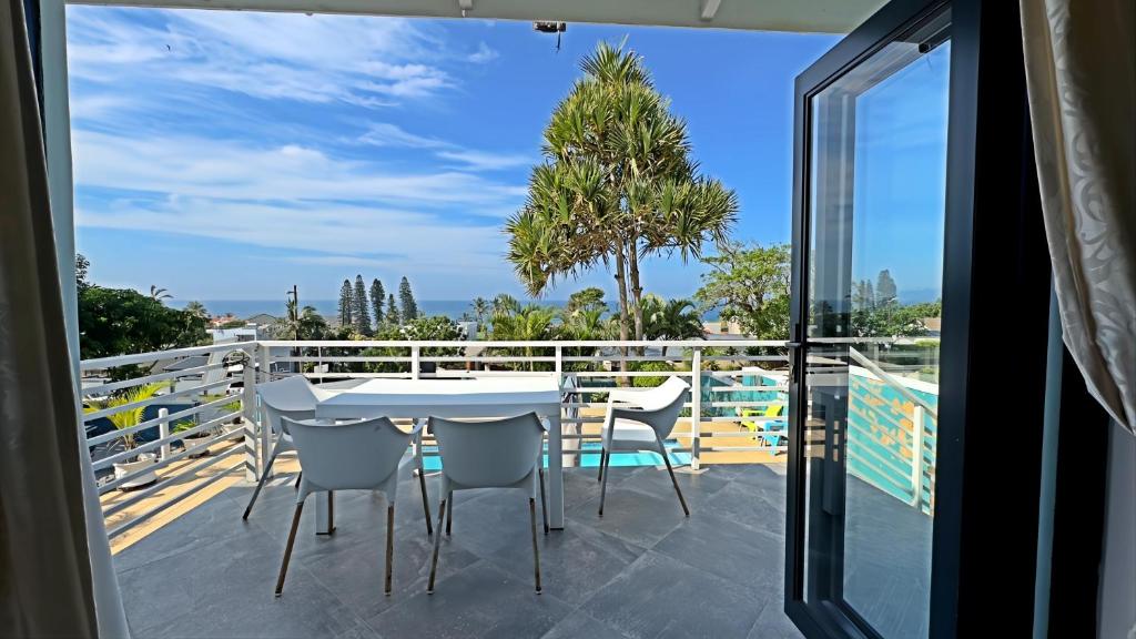 Open balcony with outdoor dining, palm trees and a view towards the sea